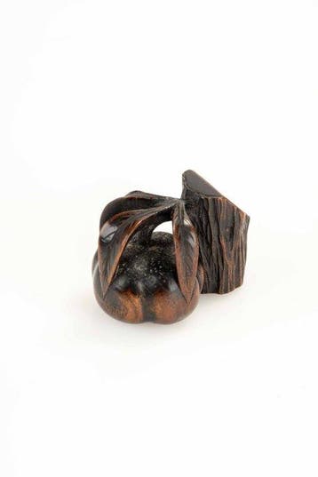 Een houten netsuke van een boomstamsnede met fruit en