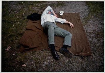 Joel Meyerowitz (1938) - Man asleep on a blanket with tihy