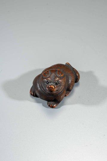 Un netsuke finement sculpté en buis représentant un chien