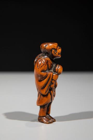 Een boxhouten netsuke van een Sennin die een lotusbloem