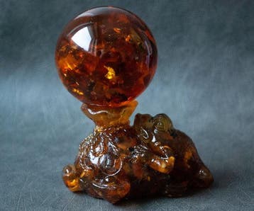 Kikker en Geldtasje Fortuin houden een amberbal vast. -