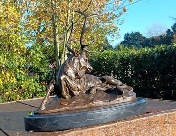 sculptuur, liggend hert met een statig gewei. - 24 cm -
