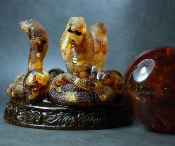 3 Baltische amber-kobras die een amberbal vasthouden. -, Antiek en Kunst