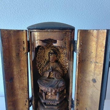 Een houten beeldhouwwerk van een zittende Kannon Bodhisattva