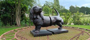 Statue, boekensteunen van een tekkel wie zijn poot optilt -