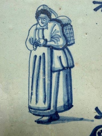 Tegel - Vrouwenfiguur met mand - Delft, Plateelbakkerij -