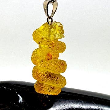 Uitgehouwen slangen- en schedelhanger in Baltisch amber met