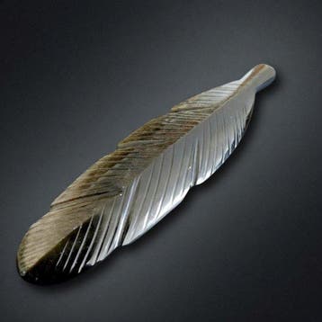 Veer gesneden uit gouden obsidiaan. Natuursteen zonder