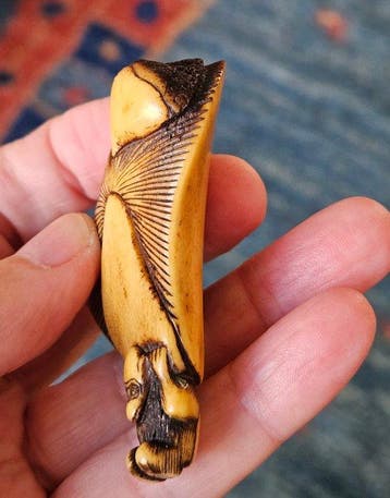 Een netsuke van een herten gewei met een aap die een