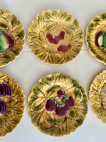 Faïence dessertborden met vruchten en blaadjes lichtjes in
