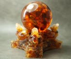 3 Baltische amber-draken die een amberbal vasthouden -